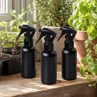 Tre sprayflaskor för bladnäring bland krukor